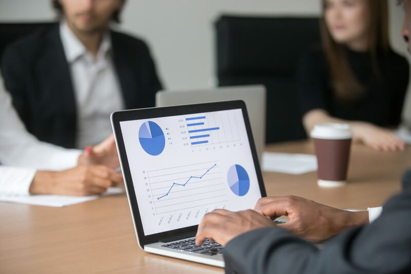 Black project manager working on computer analyzing statistics at meeting