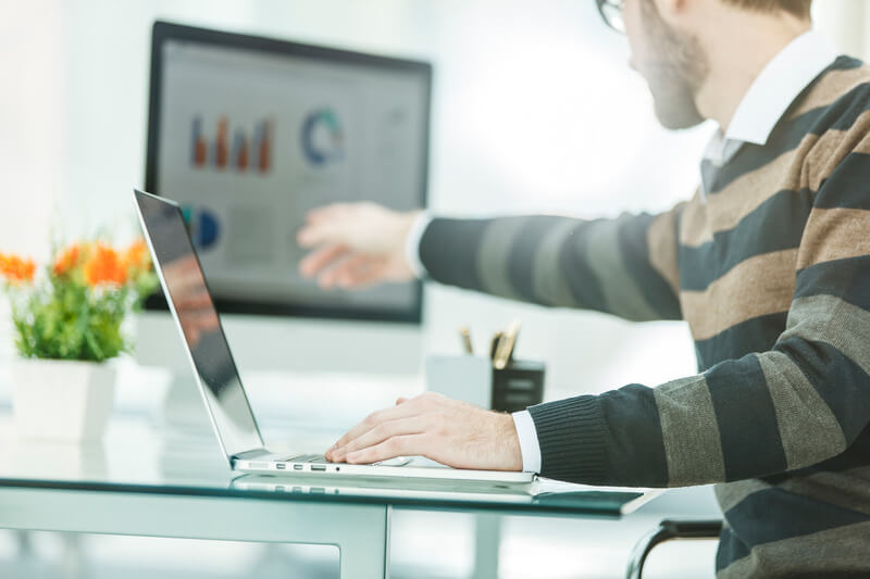 Finance specialist working on laptop with financial charts and marketing schemes
