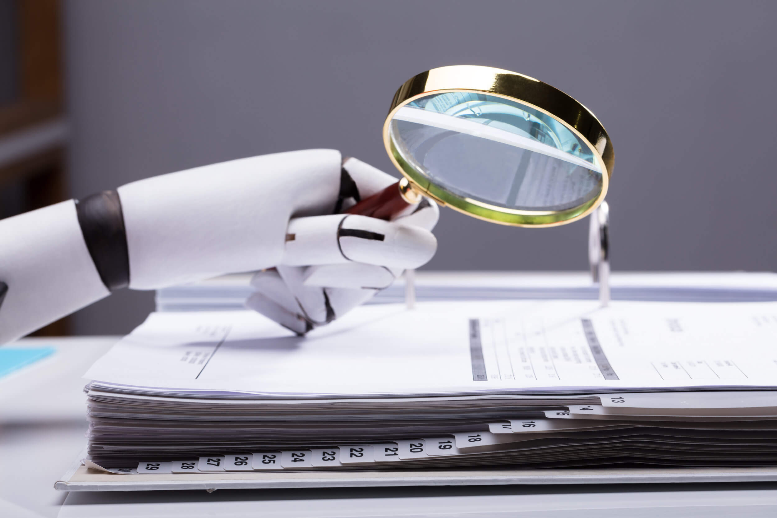 Close-up,Of,A,Robotic,Hand,Holding,Magnifying,Glass,Over,Invoice