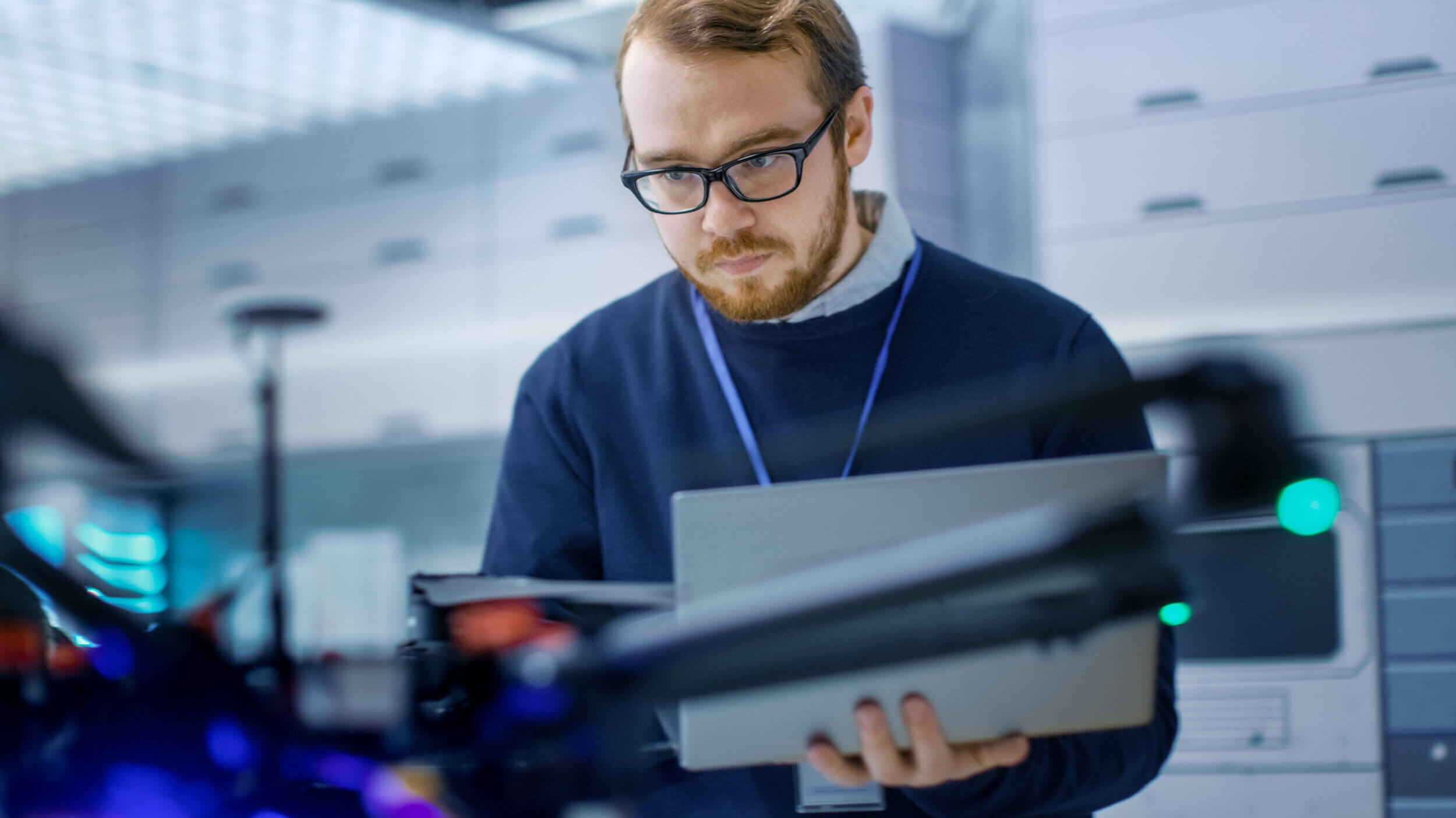 Young,Male,Engineer,Programs,Drone,While,Holding,Laptop,In,His